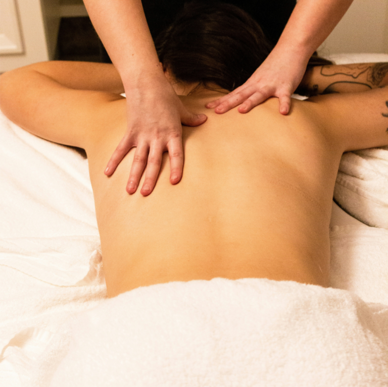 Personne recevant un massage du dos sur une table de massage, drapée de serviettes blanches, bénéficiant d'une séance efficace de gestion du stress.