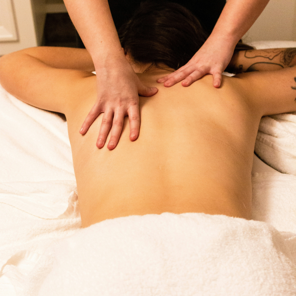 Personne recevant un massage du dos sur une table de massage, drapée de serviettes blanches, bénéficiant d'une séance efficace de gestion du stress.